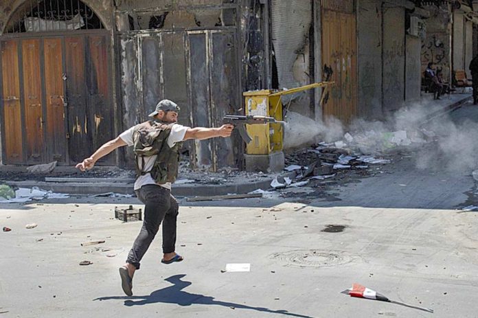 Un rebelde sirio dispara su rifle por las calles del distrito de Bab Al-Nasr. / AFP